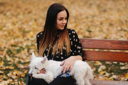 Mother and little daughter walking with her dog in autumn weather. Stylish little daughter and her beautiful mother. Happy childhood. Outdoors portrait of happy family.の写真素材