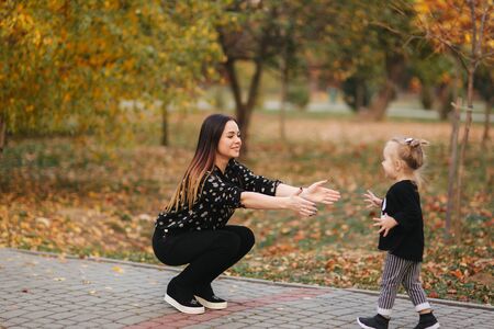 Mom and daughter spend time together in the park in autumn time. Happy family conceptの写真素材