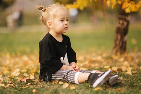 Portrait of little girl walking in the part in autumn. Blond hairl female kid outside. Warm autumn