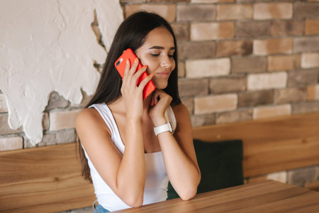 Beautiful brunette female talking on the phone in the cafe. Close ou of woman using phone