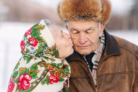 Portrait of happy senior couple. Elderly woman kiss her husband in weighty. old couple walking in the park in winter time. Happy family. Gold weddingの写真素材