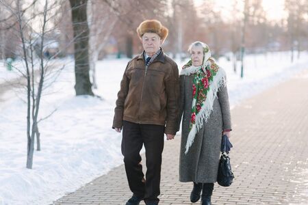 Romantic senior couple walking in the park in winter time. Love forever. Background of white winter snowの写真素材