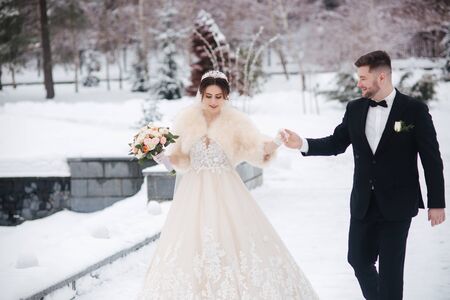 Wedding couple in winter time walking outside. Beautiful bride and handsome bearded groomの写真素材