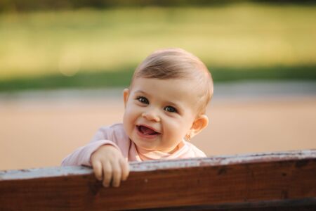 Close up of beautiful little smiled girl. Happy baby girl in autumn park. Ten month baby smileの写真素材