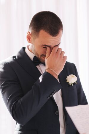 Handsome groom reading wedding vows and started crying. Groom have feeling of overwhelming love for brideの写真素材