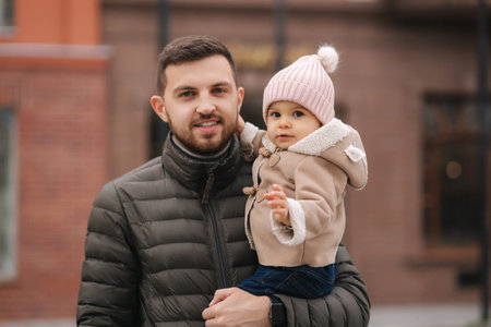 Adorable little girl on fathers hands. Cute baby girl laughing. Father with daughter in the city