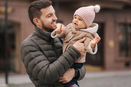 Adorable little girl on fathers hands. Cute baby girl laughing. Father with daughter in the cityの写真素材