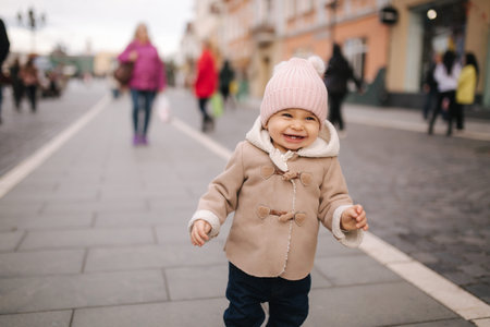 Portrait of baby girl in coat and hat laughing. Cute baby outsideの写真素材