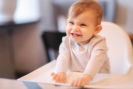 Portrait of adorable little girl on highchair. Baby laughing and play. Happy girl smile