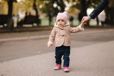 Cute little baby walking in the park with mother. Autumnの写真素材
