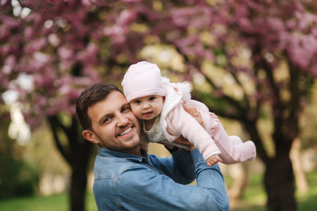 Portrait of beautiful little baby girl on fatherss hands. Happy yound father outside with cute...