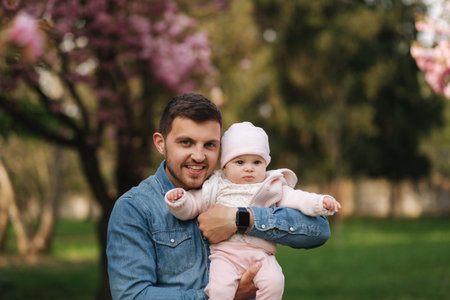 Portrait of beautiful little baby girl on fatherss hands. Happy yound father outside with cute...
