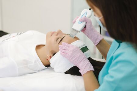 Close up of female face with soft skin. Woman at cosmetology clinic taking a beauty procedure for skin clining. Doctor with gloves on.の写真素材