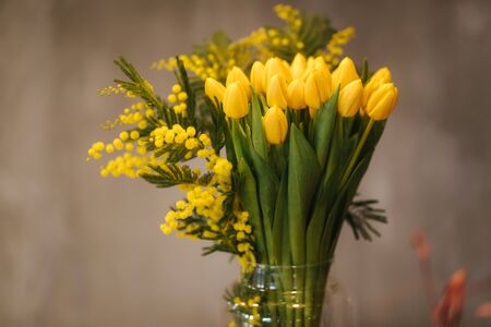 Bouquet of yellow tulips in vase on wooden tableの写真素材