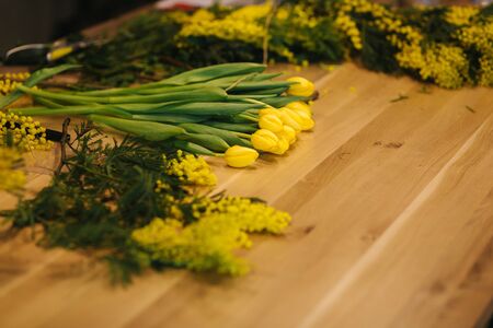 Working place of floristic. Yellow tulips lilac on wooden tableの写真素材
