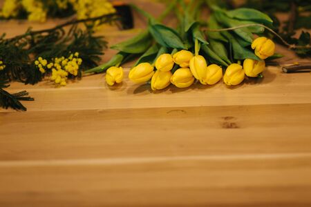 Working place of floristic. Yellow tulips lilac on wooden table.の写真素材