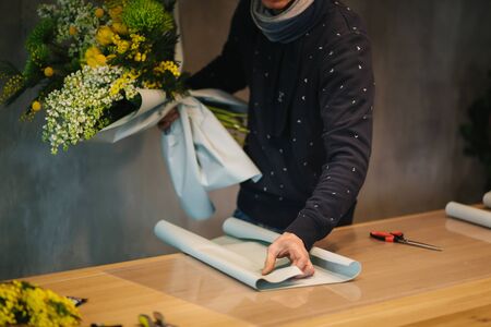 Male make spring bouquet. Gardener's in the flower shop make bouquet. Lifestyle flower shop. Beautiful flower composition of yellow flowers.の写真素材