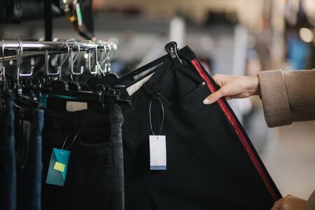 Close up of woman choosing jeans. Hand of female holding jeans in clothes store.の写真素材