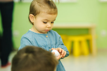 Little baby in kindergarden play. Baby girl in blue jeans shirt. Cute little baby in nursery