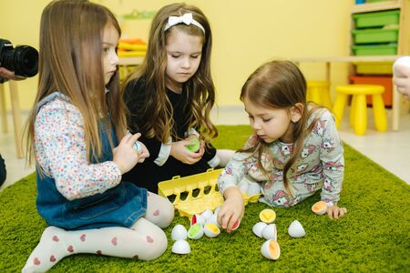 Childrens play with toy eggs in kindergarden. Nursery. Boy and girlsの写真素材