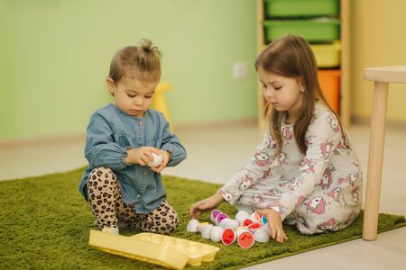 Childrens play with toy eggs in kindergarden. Nursery. Boy and girlsの写真素材