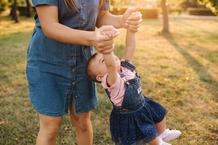 Mom play with little daughter in the park. Happy moment. Cute baby with beautiful mom.の写真素材