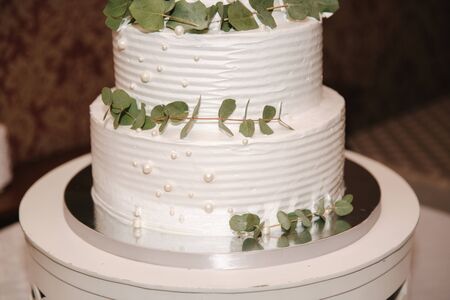 Beautiful white wedding cake with decorated by green leafs.の写真素材