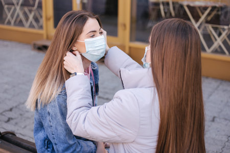 Girls in masks. Coronavirus theme. Women in the city walks during quarantine. Help to put on a mask