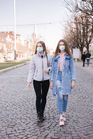 Girls in masks. Coronavirus theme. Women in the city walks during quarantineの写真素材