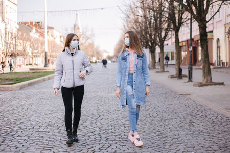 Girls in masks. Coronavirus theme. Women in the city walks during quarantine