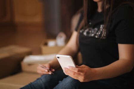 Young woman open new parcel with clothes. Woman hepl to sell secound hand goodsの写真素材