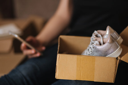 Young woman open new parcel with clothes. Woman hepl to sell secound hand goods