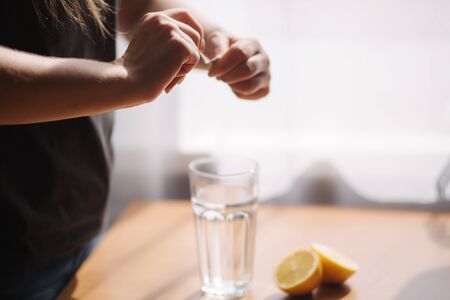 Females hands put aspirin in glass with water. Coronavirus conceptの写真素材