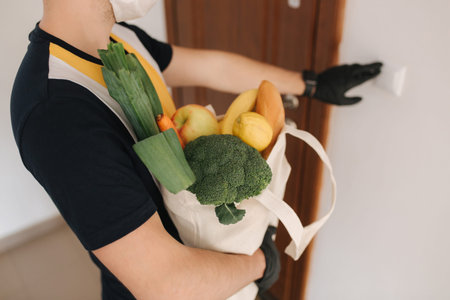 Delivery man in mask and gloves bring fresh food to customers home. Stay home. Online shopping...