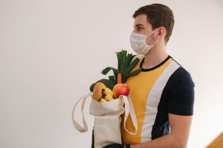 Delivery man in mask and gloves bring fresh food to customers home. Stay home. Online shopping conceptの写真素材