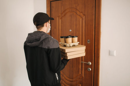 Man delivery pizza and coffe to customer in mask and gloves. Coronavirus theme