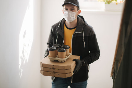 Man delivery pizza and coffe to customer in mask and gloves. Coronavirus theme