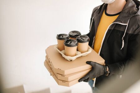 Man delivery pizza and coffe to customer in mask and gloves. Coronavirus themeの写真素材