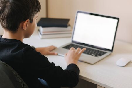 Teenage boy studing on paltip at home. Young boy play online games at home. Study in quarantine. Happy schoolboy during qurantineの写真素材