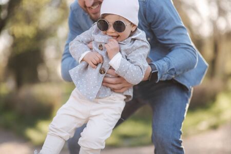 Happy cute daughter on fathers hand. Dad and daughter walk in the park. Family mood. Little gil laughの写真素材