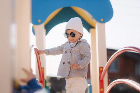 Cute little girl walk in playground and have fun. Adorable girl in stylish clothes.