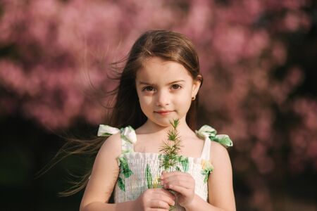 Portrait of adorable little girl on the fresh air walking in the park, background of sakura treeの写真素材
