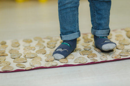 Kid walk on a massage mat in preschool. Close up of kids foot