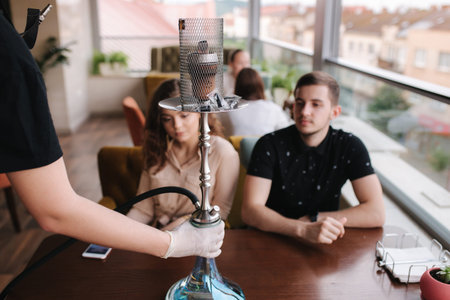 Hookahman bring hookah for customer. Group of friends in restaurant