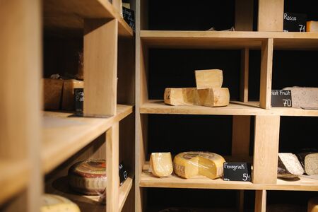 Shelf with cheese in cheese store. Assortment of different cheese typesの写真素材