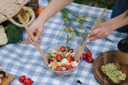 Woman mix vegan salad on picnic outside. Vegan food conceptの写真素材