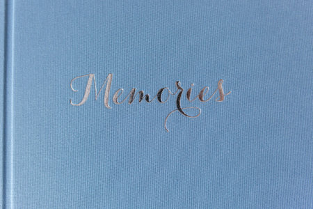 Close up of Closed photobook on white wooden table. Blue wedding album with silver embossing