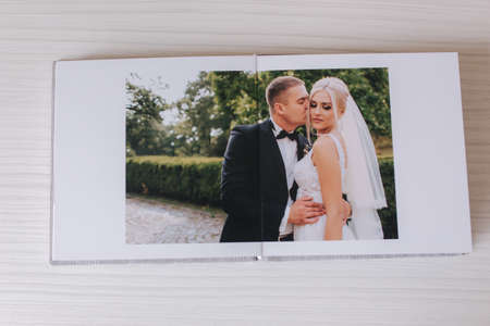 Open photobook with wrdding photo of beautiful couple on white wooden tableの写真素材