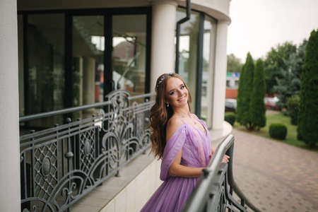 Portrait of elegant woman in purple evening dress walking outdoors by restaurantの写真素材