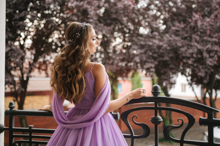 Back view of woman in evening dress stand on terrace and smile. Beautiful hairsyle
